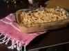 Fotografia de um prato de salpicão cremoso em uma travessa de vidro, com cenouras raladas, passas, azeitonas e um toque festivo, decorado com um pano vermelho e branco, sugerindo um ambiente acolhedor e de celebração.