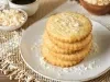 Em cima de uma mesa prato redondo, com biscoitos amanteigados enfileirados, decorado com coco ralado.