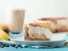 Em cima de uma mesa, fatia de banoffe com massa crocante, decorado com chantily e canela em pó.