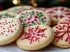 Em cima de uma mesa, prato redondo com biscoitos redondos, decorados com glacê branco e confeitos coloridos.