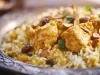 Um prato de Arroz Natal é apresentado em um prato, repleto de arroz soltinho e colorido. O arroz é misturado com pedaços suculentos de peito de frango, ervilhas verdes e uvas-passas.