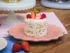 Image da receita de Mini Bolo Bem-Casado com Renda de Açúcar da Beca Milano, sobre um prato rosa, em uma bancada de madeira, decorado com frutas vermelhas e uma plaquinha com os dizeres Beca Milano em dourado