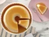 Imagem vista de cima de um prato branco com o pudim de gelatina cortado. Ao lado, um prato rosa claro com uma fatia e um garfo.