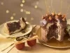 Fotografia em tons de amarelo em uma bancada de madeira clara, um pano amarelo e decoração natalina de fundo. Ao centro, um prato dourado com o panettone de avelã recheado sem um pedaço. Ao lado, um prato com a fatia do panettone.