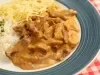 Foto tirada de cima de um prato azul com strogonoff de carne dentro, arroz e batata palha