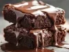 Um pedaço de bolo de chocolate empilhado sobre outro, ambos com uma cobertura generosa de calda de chocolate derretido escorrendo pelas laterais. A textura é úmida e densa, com aparência extremamente saborosa.