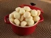 Em cima de uma mesa, recipiente redondo com biscoitos amanteigados redondos e dourados.