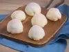 Receita de Mochi de Brigadeiro, servida em pequenas bolinhas brancas, recheadas com brigadeiro enrolado, sobre uma tábua de madeira e um tecido na cor azul ao lado de uma Lata de Leite Moça