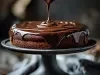 Fotografia de um bolo de chocolate sendo coberto com ganache brilhante e cremoso, posicionado em um suporte escuro. A imagem destaca a textura cremosa do chocolate.