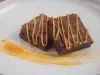 Foto aproximada de duas fatias cortadas da receita de brownie clássico de chocolate, decoradas com fios de doce de leite feito com Leite Moça cozido