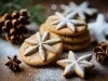 Em cima de uma mesa, prato com biscoito redondo em formato de estrelas, decorado com açúcar de confeiteiro.