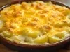 Em cima de uma mesa, refratário com batatas com queijo gratinado.