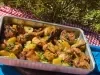 Frango assado dourado com batatas em rodelas levemente crocantes nas bordas, tudo coberto com cebolas caramelizadas e cheiro-verde fresco. Servido em assadeira rústica sobre mesa de madeira.