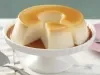 Imagem de uma boleira branca com o pudim de gelatina cortado com uma fatia separada.