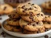 Imagem de um prato com cookies com gotas de chocolate empilhados. Ao lado, mais cookies e gotas de chocolate.