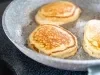 Imagem aproximada de uma frigideira cinza com três pães de aveia redondos.
