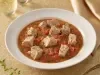 Goulash moderno de atum servido em prato fundo, com cubos de peixe em molho de tomate encorpado e ervas frescas.