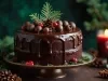 Fotografia de um bolo de chocolate decorado, com ganache brilhante escorrendo pelas laterais. O bolo é enfeitado com trufas de chocolate, frutas vermelhas e ramos de pinheiro, criando um ambiente festivo.