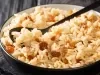 Em cima de uma mesa, tigela com uma colher preta com arroz soltinho com uvas-passas brancas.