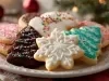 Em cima de uma mesa, prato branco com biscoitos em formato de Árvore de Natal e estrelas, decorados com glacê colorido, chocolate derretido e confeito colorido.