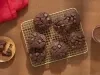 Fotografia de uma grelha quadriculada ao lado de um copo de vidro com leite e nescau e um mini apoio circular de madeira com um cookie ao meio. Sobre a grelha tem sete cookies de nescau extra cacau com gotas de chocolate. Fotografia de uma grelha quadriculada ao lado de um copo de vidro com leite e nescau e um mini apoio circular de madeira com um cookie ao meio. Sobre a grelha tem sete cookies de nescau extra cacau com gotas de chocolate.