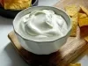 Imagem de um bowl branco com requeijão cremoso e nachos ao lado.