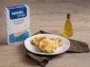 Foto da receita de pizza de abobrinha com aveia servida em 3 porções em um prato branco sobre um pano marrom escuro em cima de uma mesa de madeira com um dispenser de azeite feito de vidro ao lado direito