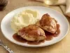 Pedaços de frango dourados servidos com purê cremoso de batata e molho escuro reduzido, apresentados em prato branco elegante