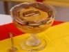 Taça de pavê com creme caramelizado e pedaços de chocolate, sobre toalha amarela e vermelha.