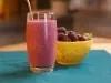 imagem mostra um copo de refresco vermelho cremoso preparado com morangos, amoras e mirtilos