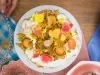 Foto vista de cima do Bolo de Frutas Amarelas, decorado com flores comestíveis, polpa de maracujá e pedaços de manga