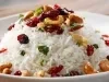 Prato de arroz branco, soltinho, com uma textura leve e fofa, com uvas-passas pretas e castanhas, decorado com cheiro-verde picado.