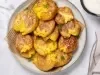 Em cima de uma mesa, prato redondo com batatas ao murro douradas e crocantes.