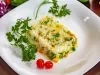 Em um prato de porcelana branco, há um porção colorida de arroz amarelo, milho verde,  ervilha, decorados com tomate cereja e galhos de coentro.