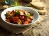 Imagem de um bowl com caponata de berinjela e ao fundo, fatias de pão.