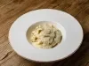 Imagem de um prato branco fundo com macarrão coberto com molho de queijo e queijo ralado.