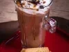 Foto da receita vista de cima de cappuccino crocante servida em uma caneca alta de vidro sobre uma mesa de madeira