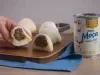 Receita de Mochi de Brigadeiro, servida em pequenas bolinhas brancas, recheadas com brigadeiro enrolado, sobre uma tábua de madeira e um tecido na cor azul ao lado de uma Lata de Leite Moça