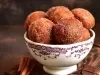 Em cima de uma mesa, tigela com bolinhos redondo, polvilhado com açúcar e canela.