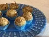 Close de docinhos cobertos com lascas de coco tostado, em forminhas azuis sobre prato azul.