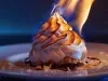 Sobremesa Baked Alaska com merengue dourado maçaricado em prato preto e fundo escuro iluminado