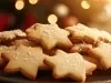 Em cima da mesa, prato com biscoitos crocantes em forma de estrela, decorado confeito branco de bolinhas.