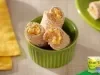 Enroladinhos de pão recheados com cenoura e ovo cremosos, cortados em pedaços e servidos em tigela verde, sobre mesa clara.