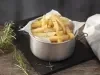 Imagem de um pote de alumínio forrado com papel e batatas fritas dentro. Ao lado, ramos de alecrim.
