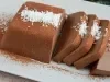 Em cima de uma mesa, prato branco com Bavaroise cortados em fatias, decorado com coco ralado.