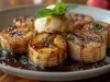 Em cima de uma mesa, prato redondo com bananas fritas cortadas em rodelas, no meio sorvete de coco, decorado com folha de hortelã.
