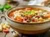 Imagem da receita de sopa de macarrão e feijão italiana, servida e uma tigela de cerâmica marrom.