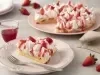 Imagem de um prato com uma fatia de torta coberta com merengue, morangos e calda. Ao fundo, uma prato rosa claro com a torta.