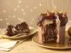 Fotografia em tons de amarelo em uma bancada de madeira clara, um pano amarelo e decoração natalina de fundo. Ao centro, um prato dourado com o panettone de avelã recheado sem um pedaço. Ao lado, um prato com a fatia do panettone.