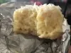 Bolo gelado de coco cortado ao meio, coberto com coco ralado e apoiado sobre papel-alumínio.